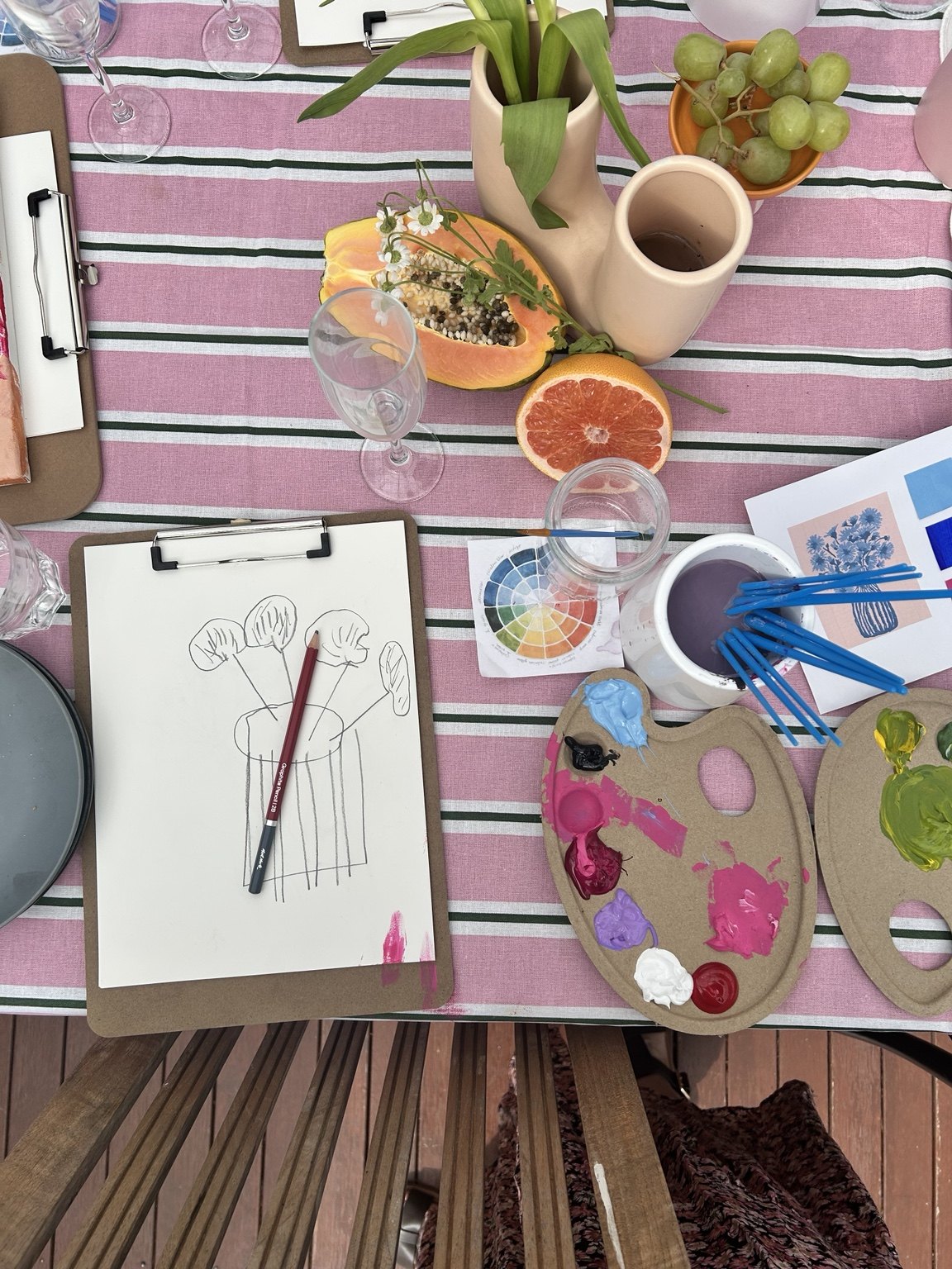 Sketchbook, paint palettes, brushes and colourful workshop materials on the table