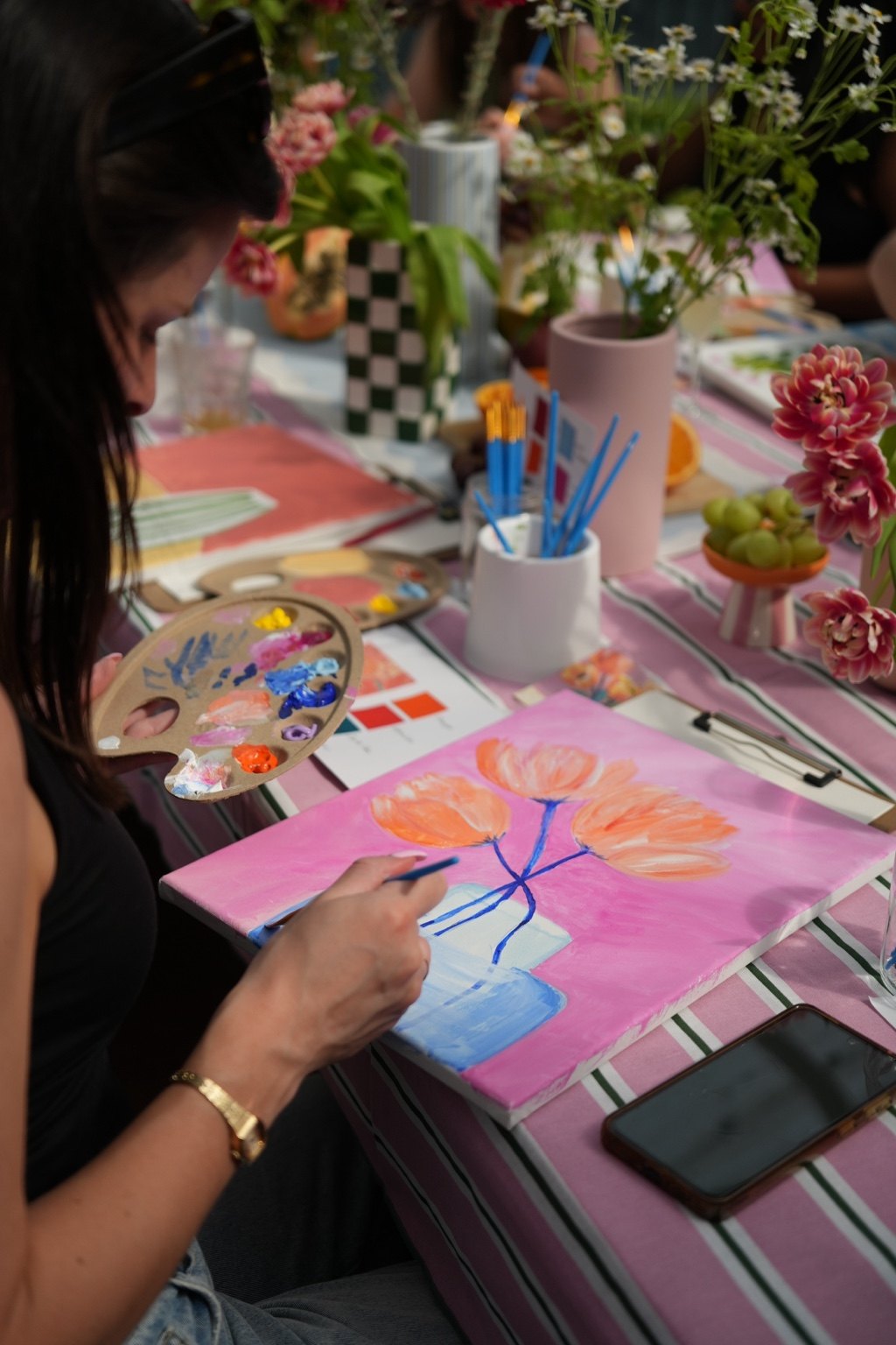 Guest painting a bright floral canvas at a Making Little Moments workshop